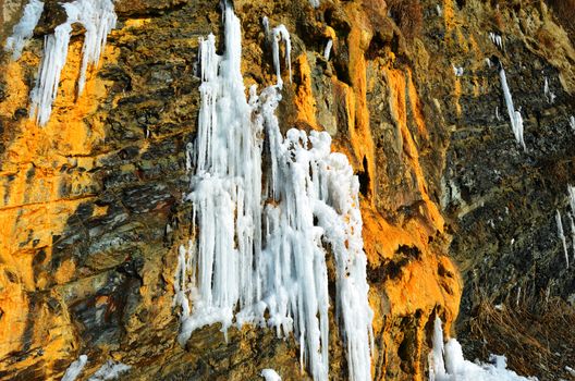 Steep rock with a frozen waterfall near the sea