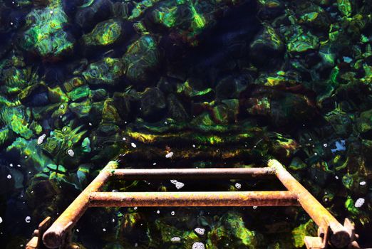 Iron stairs, disappearing into the clear sea water and rocks on the bottom