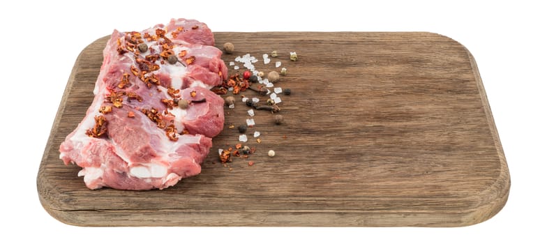raw pork ribs with chili peppers on cutting board isolated on white.