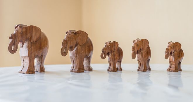 Carved wooden elephants on white table in the room
