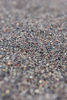 Dry black volcanic sand from Santorini background. Selective focus.