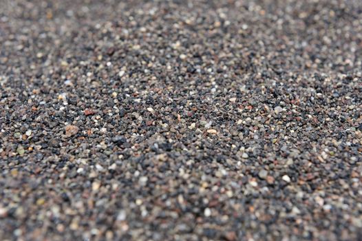Dry black volcanic sand from Santorini background. Selective focus.