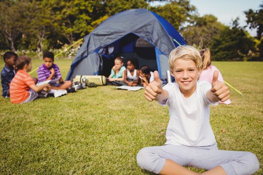 Happy child doing thumbs up during a sunny day at park