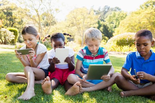 Kids using technology during a sunny day at park