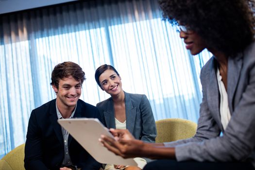 Business people having a discussion around a tablet computer in office