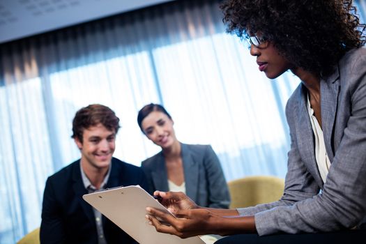 Business people having a discussion around a tablet computer in office