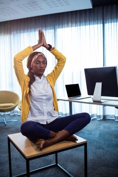 Portrait of businesswoman doing yoga at the office