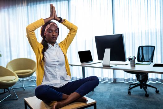 Businesswoman doing yoga at the office