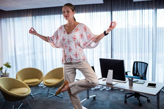 Businesswoman doing yoga on a table in the office