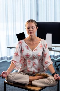 Portrait of businesswoman doing yoga at the office