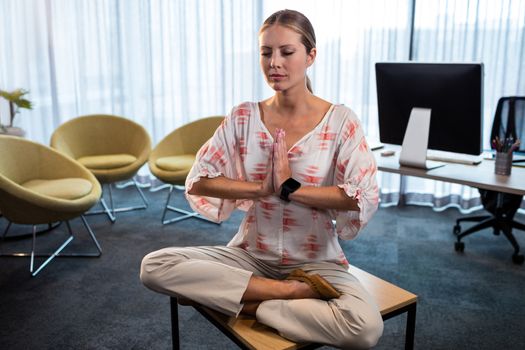 Businesswoman doing yoga with hands tied in the office
