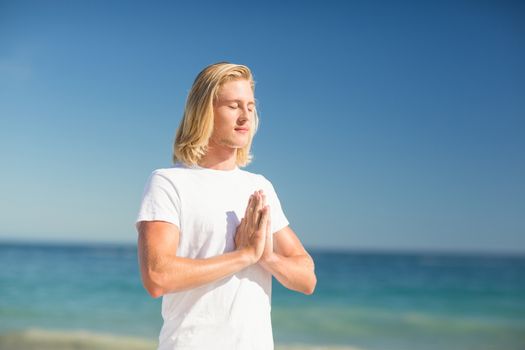 Young man performing yoga on beach