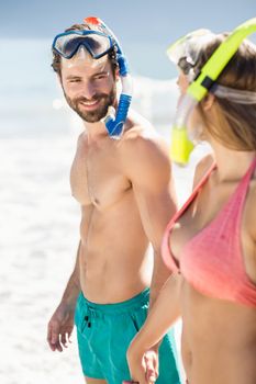 Happy young couple holding hands and standing on beach