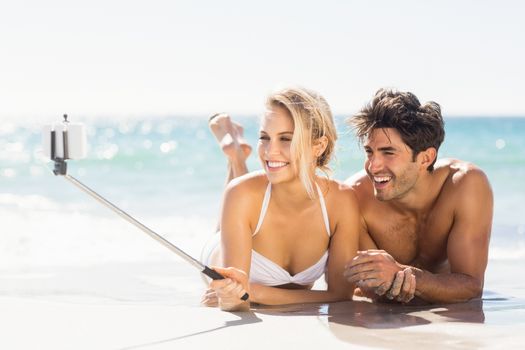Young couple taking selfie with selfie stick on beach
