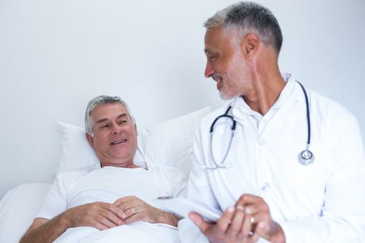 Male doctor and senior man interacting with each other in hospital