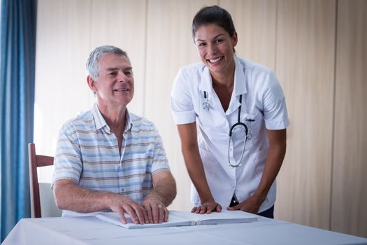 Female doctor helping patient in reading the braille book at home