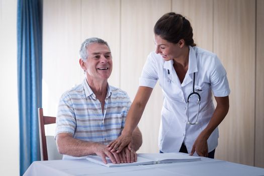 Female doctor helping patient in reading the braille book at home