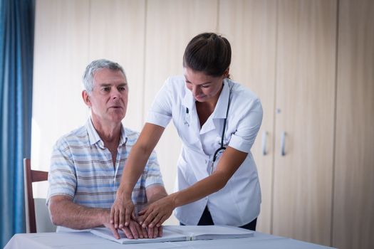 Female doctor helping patient in reading the braille book at home