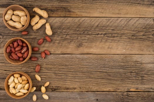 Peanuts in wooden masks on the old wooden table. Top view.