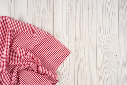 Red folded tablecloth over bleached wooden table. Top view.