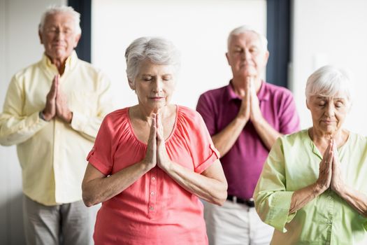 Seniors doing yoga with closed eyes in a retirement home
