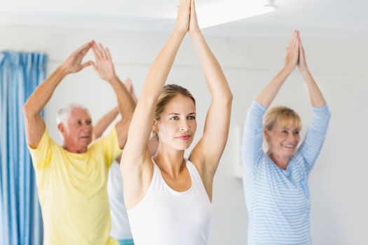 Instructor performing yoga with seniors during sports class