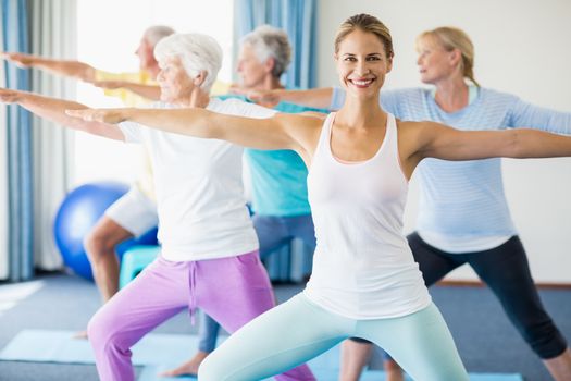 Instructor performing yoga with seniors during sports class