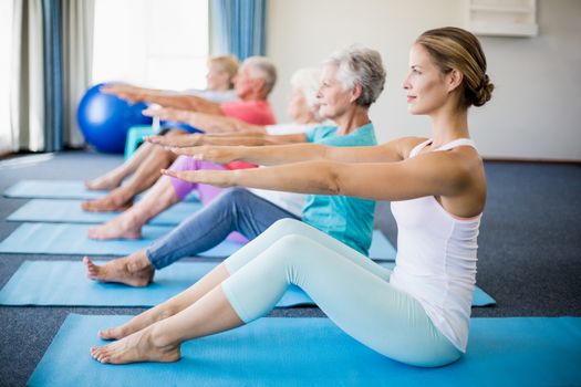 Instructor performing yoga with seniors during sports class