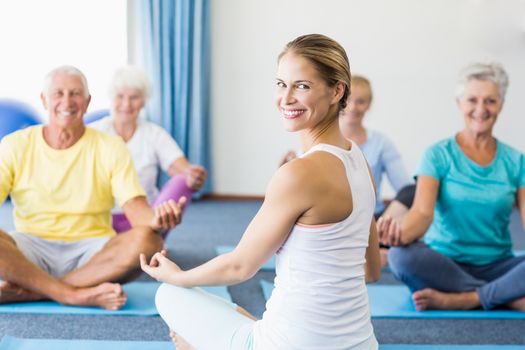 Instructor performing yoga with seniors during sports class