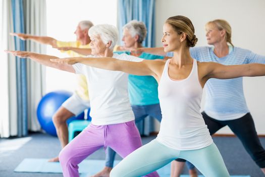 Instructor performing yoga with seniors during sports class