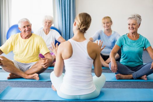 Instructor performing yoga with seniors during sports class