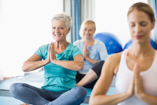 Instructor performing yoga with seniors during sports class