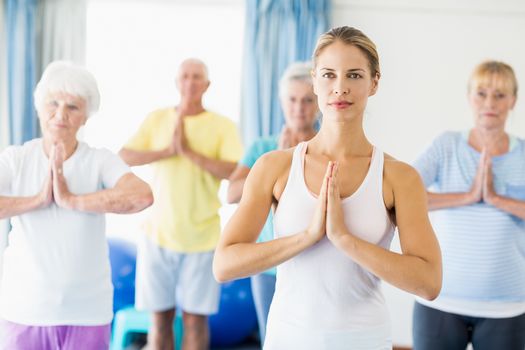 Instructor performing yoga with seniors during sports class