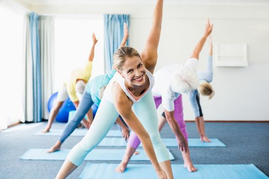 Instructor performing yoga with seniors during sports class