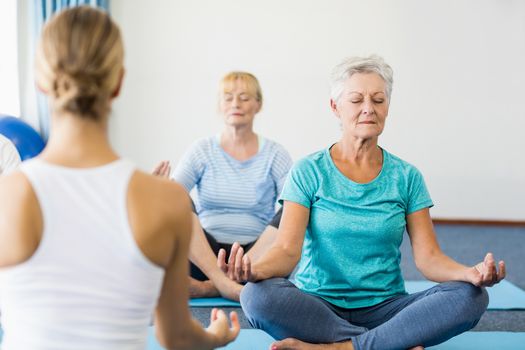 Instructor performing yoga with seniors during sports class