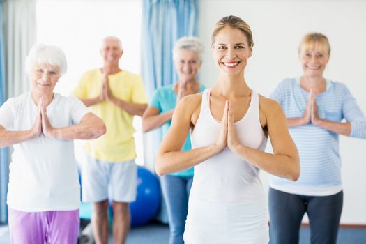 Instructor performing yoga with seniors during sports class