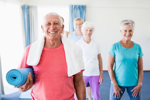 Senior man holding yoga mat during sports class