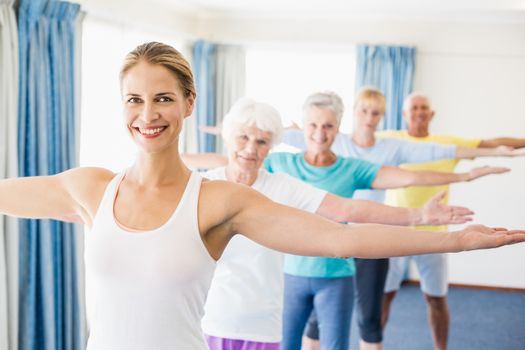 Instructor performing yoga with seniors during sports class