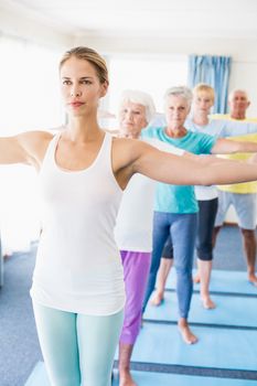 Instructor performing yoga with seniors during sports class