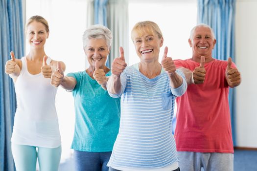 Instructor and seniors with thumbs up in a studio