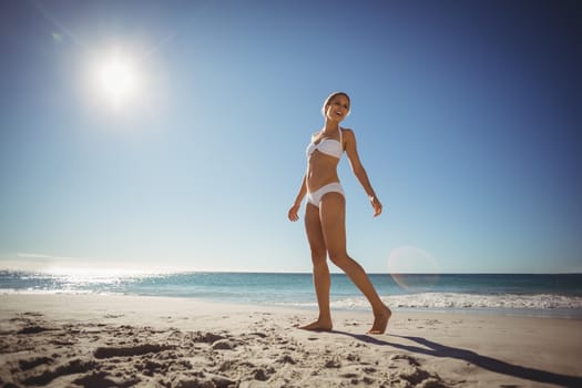 Beautiful young woman walking on beach in summer