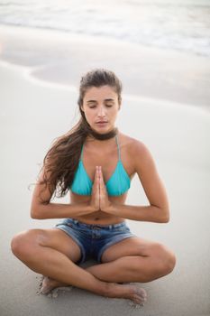 Young woman performing yoga on the beach