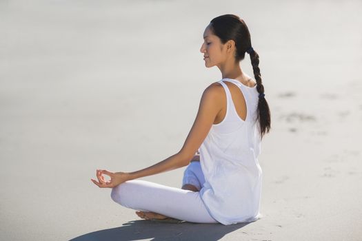 Young woman performing yoga on the beach