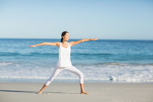 Young woman doing yoga on the beach