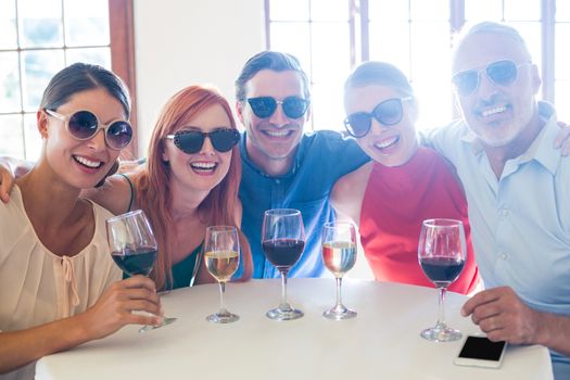 Group of friends in sunglasses posing with drinks in restaurant