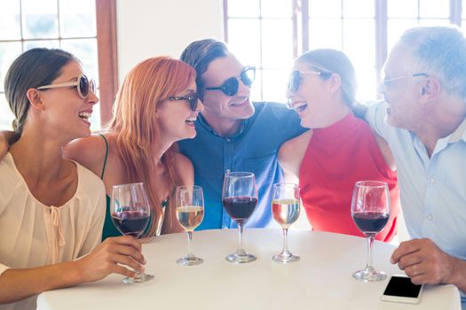 Group of friends in sunglasses laughing and talking in restaurant