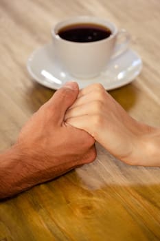 Close-up of couple holding hands in cafeteria