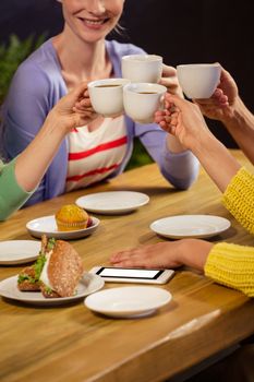 Smiling friends drinking coffee in the cafe