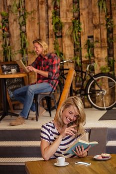 People reading book and using tablet in the cafe