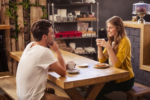 Two smiling hipsters drinking coffee at coffee shop